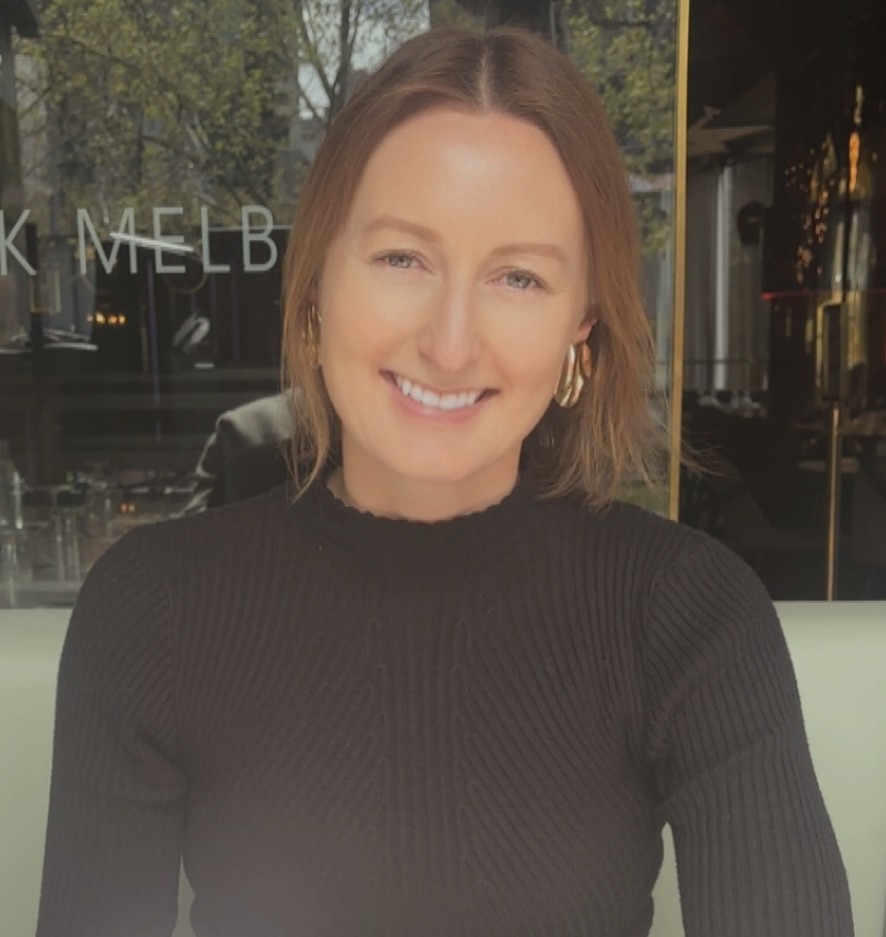 Smiling person in a black sweater indoors.