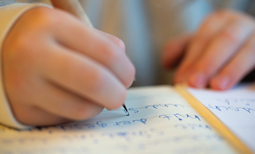 Close-up of hand writing in notebook