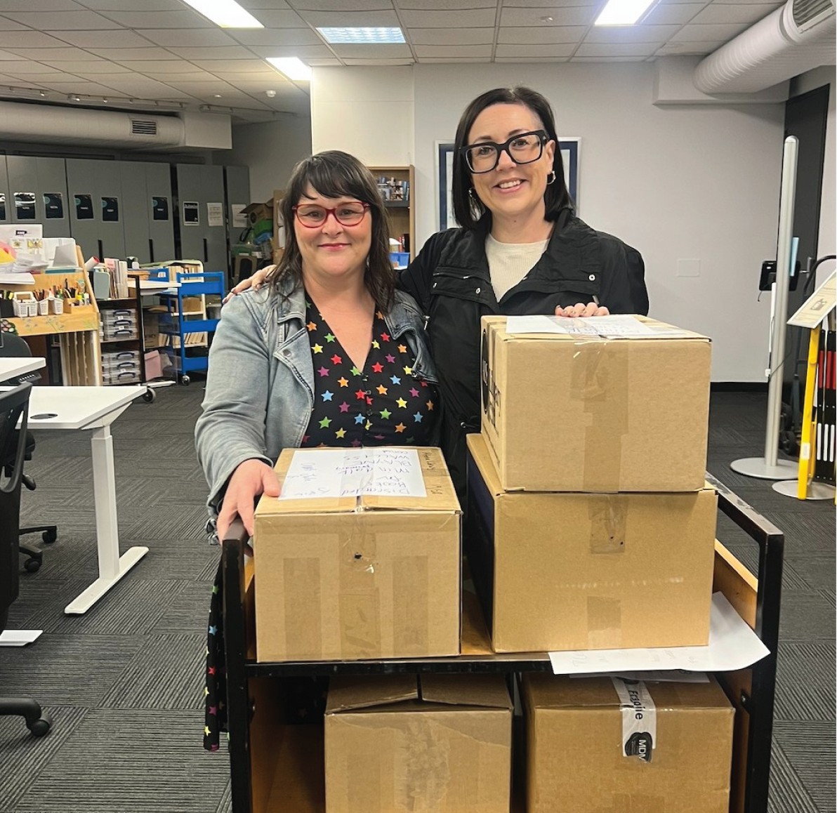 Two women with boxes in an office