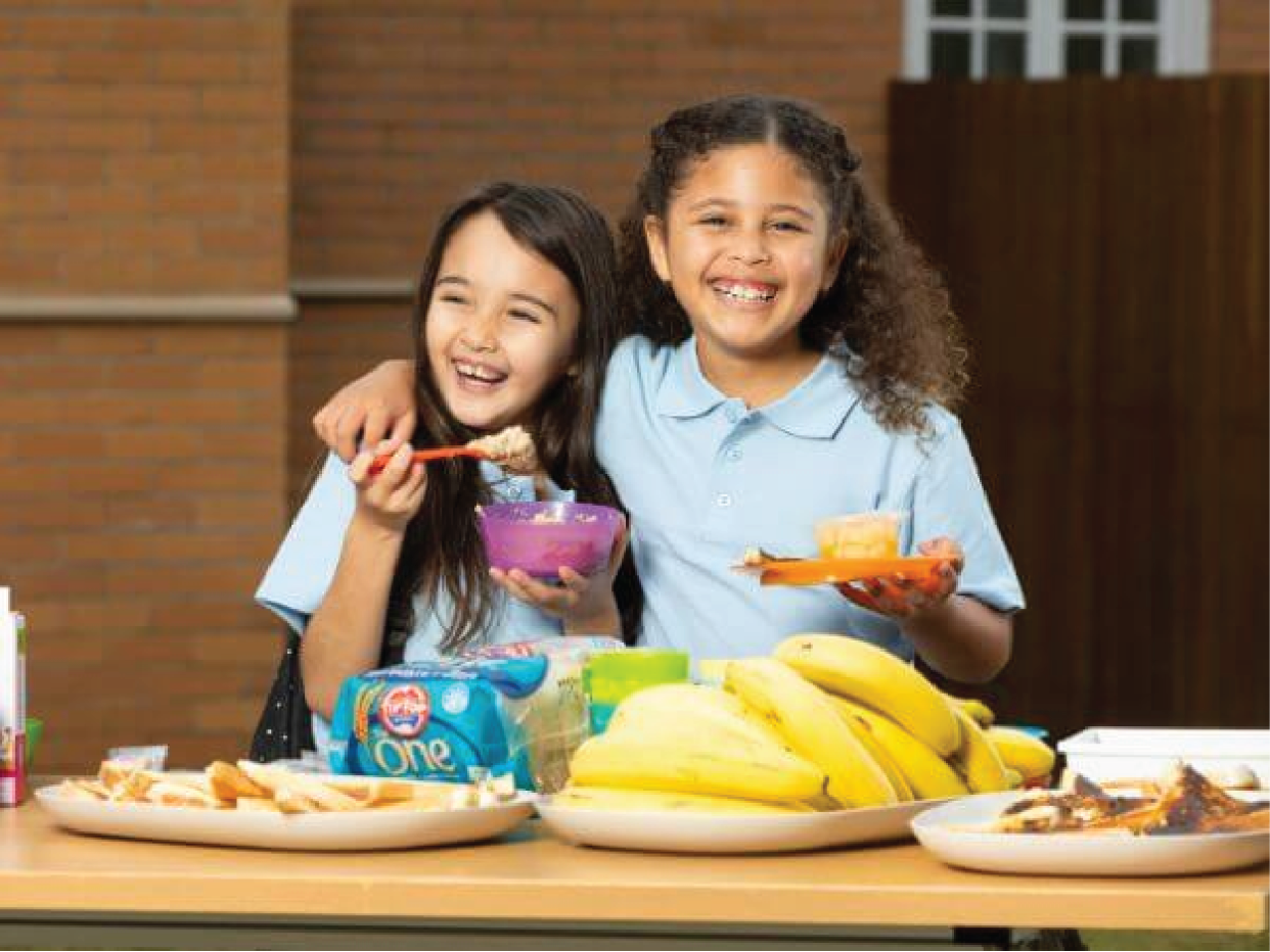 Two children laughing, enjoying breakfast together.