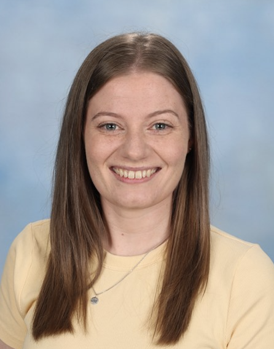 Smiling woman in yellow shirt, blue background.