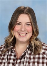 Smiling person with brown hair and plaid shirt.