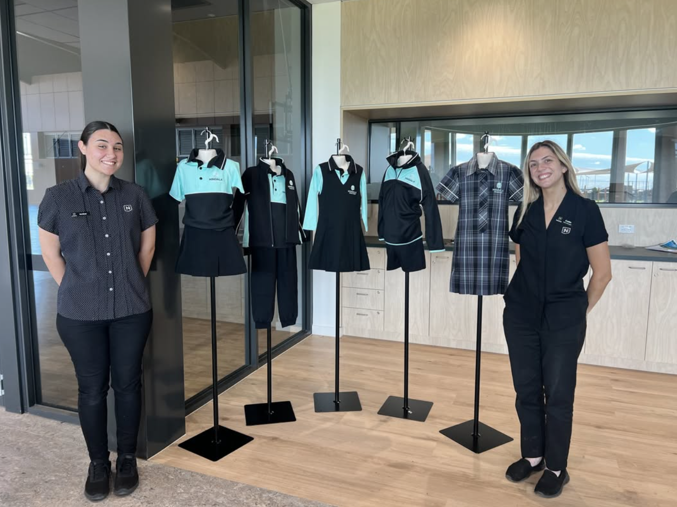 School uniforms displayed with two staff members