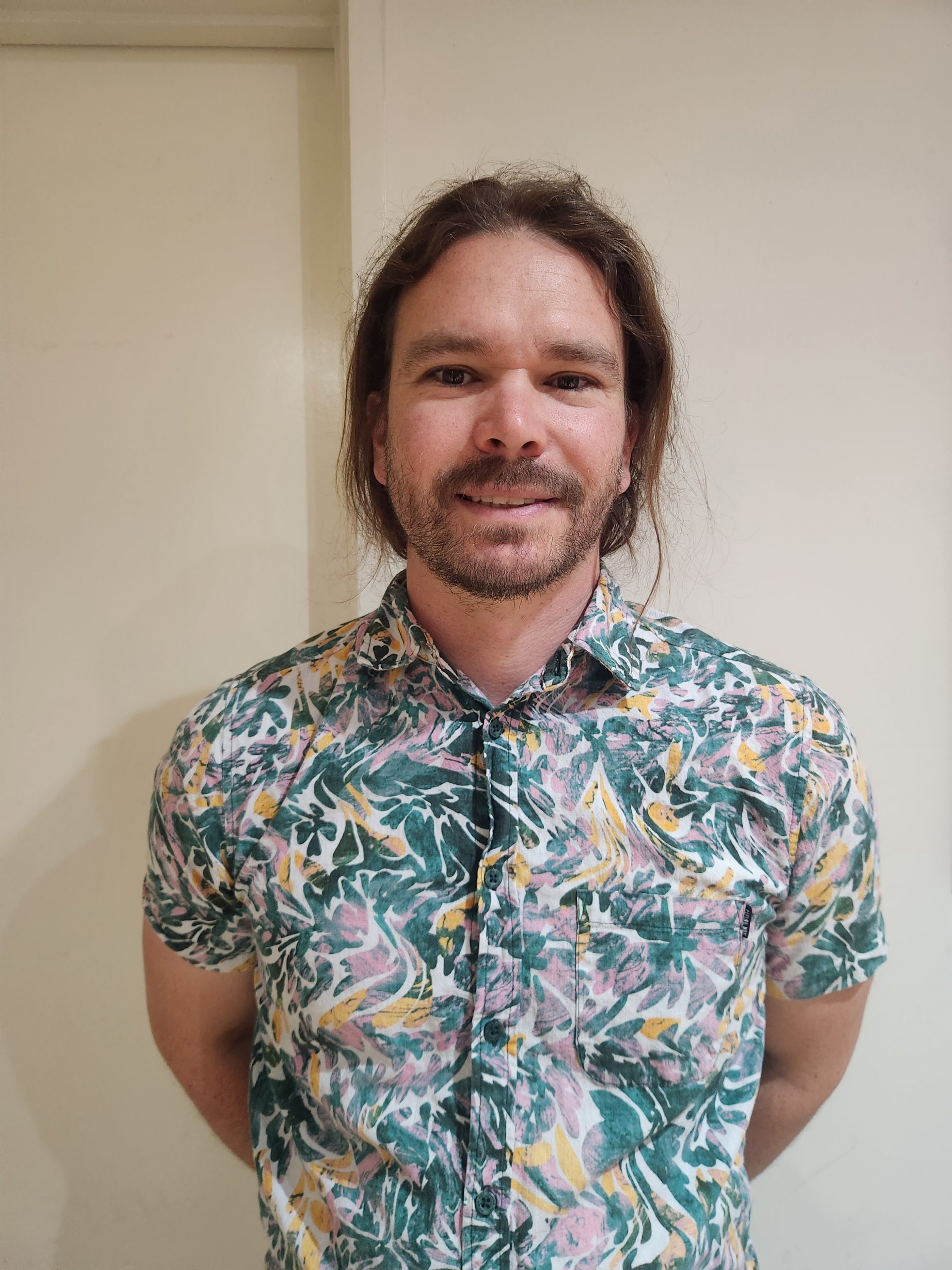 Person in colourful floral shirt standing indoors.