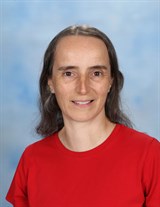 Smiling person in red shirt with blue background.