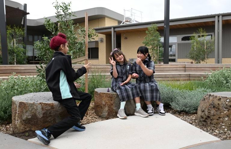 Children in school uniforms playing outside building.