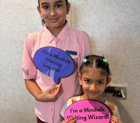 Two children holding literacy award signs.